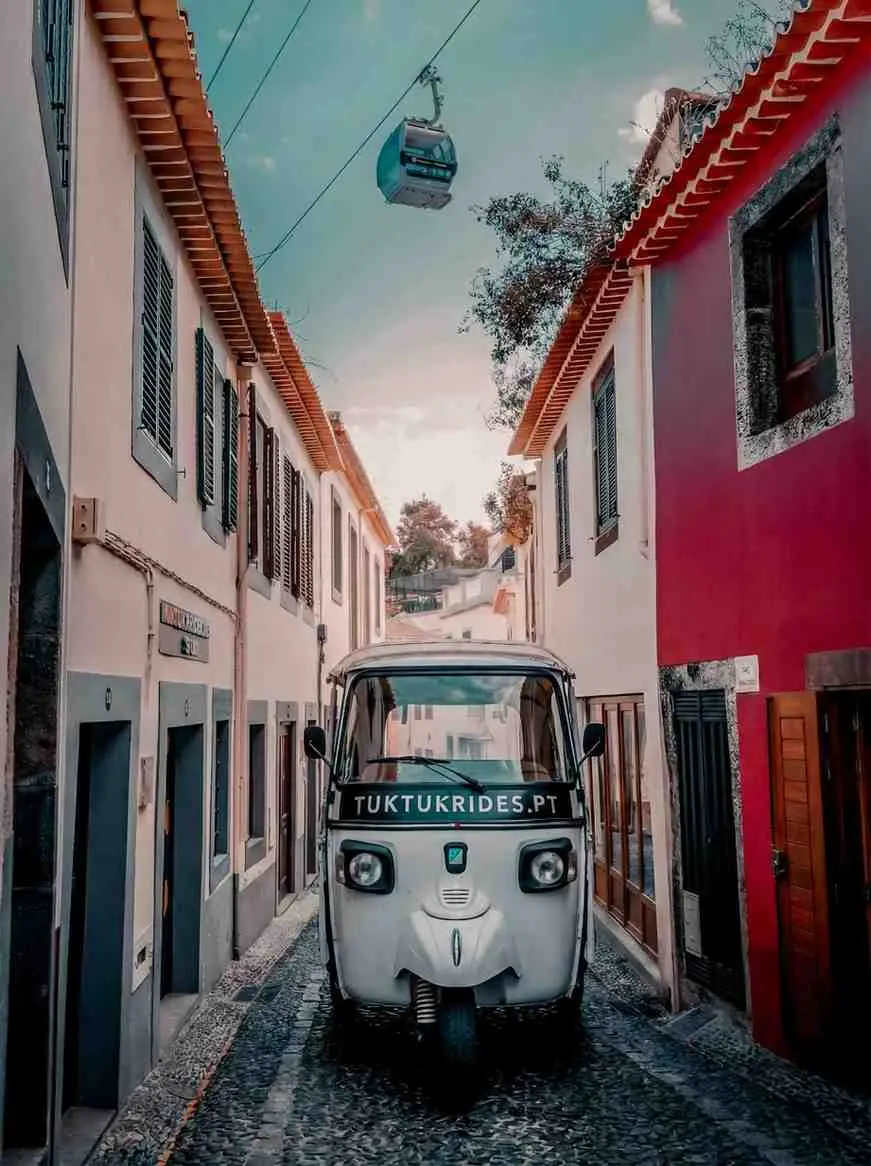 TukTukRides tuk tuk in a cobbled Old Town street in Funchal under the cable car